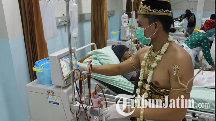 Seorang karyawan RSUD dr Iskak mengenakan pakaian adat Jawa, tengah memberikan layanan kepada seorang pasien cuci darah.