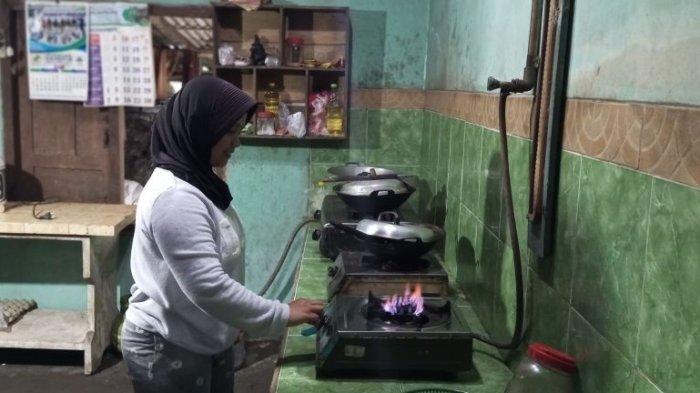 Dewi Astuti warga Balong Wetan, Umbulharjo, Cangkringan, Kabupaten Sleman DI Yogyakarta sedang memasak menggunakan api biru yang bersumber dari biogas hasil pengolahan kotoran sapi.
