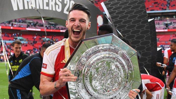 Gelandang Arsenal, Declan Rice, mengangkat trofi Community Shield 2023 yang dimenangkan timnya usai taklukkan Manchester City lewat babak adu penalti, Minggu (6/8/2023).