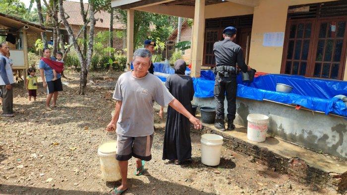 Seorang warga Dusun Bleber, Desa Sambeng, Kecamatan Bayan, Kabupaten Purworejo, Jawa Tengah, membawa pulang ember berisi air bersih yang disalurkan Brimob Batalyon 4C Kutoarjo, Senin (4/9/2023).