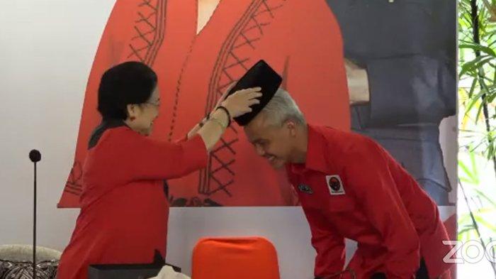 Ketua Umum PDIP Megawati Soekarnoputri menyematkan kopiah hitam pada Ganjar Pranowo saat pengumuman calon presiden di Istana Batu tulis, Bogor, Jumat (21/4/2023). (YouTube / PDI Perjuangan)