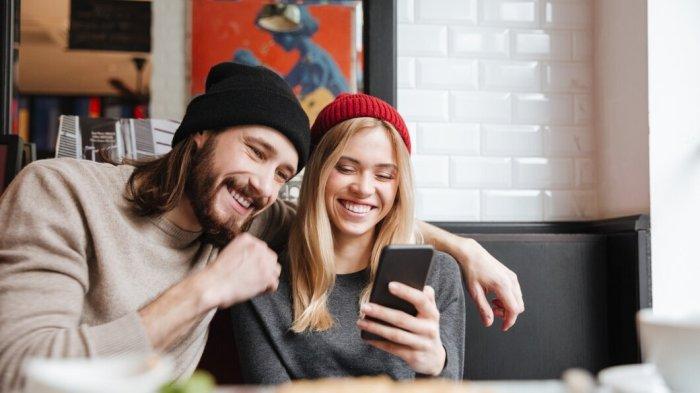 PANTUN TEKA-TEKI CINTA - Potret pasangan tertawa melihat handphone dari Freepik.com, Rabu (30/4/2025). Simak kumpulan pantun teka-teki cinta berikut ini, cocok jadi bahan seru-seruan bareng pasangan biar hubungan nggak monoton dan makin berwarna.