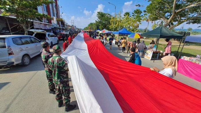 Ratusan santri berbaur dengan warga Tanjung Selor, Bulungan membentangkan Bendera Merah Putih sepanjang 1022 meter di Tepian Sungai Kayan, Tanjung Selor, Minggu (22/10/2023). (Tribunkaltara.com/Edy Nugroho)
