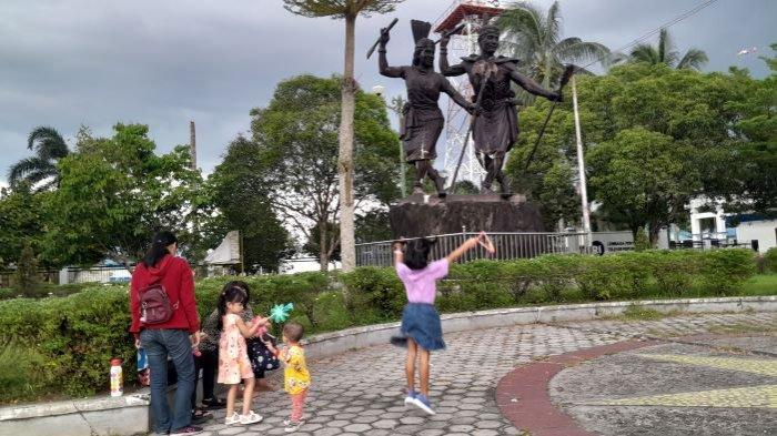 Masyarakat Kota Palangkaraya sedang mengabadikan diri berfoto berlatar belakang patung sepasang penari dayak perempuan dan laki-laki berpakaian khas Dayak Kalteng di jalan Yos Sudarso, Selasa (21/2/2023).