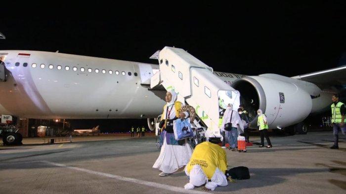 Jemaah haji yang baru turun dari pesawat langsung bersujud syukur tepat di samping badan pesawat yang sedang menurunkan penumpang. 