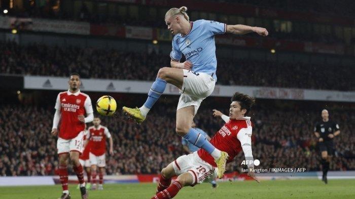 Penyerang Manchester City Erling Haaland (biru) berebut bola dengan bek Arsenal Takehiro Tomiyasu dalam pertandingan Liga Inggris di Stadion Emirates, London, 15 Februari 2023.