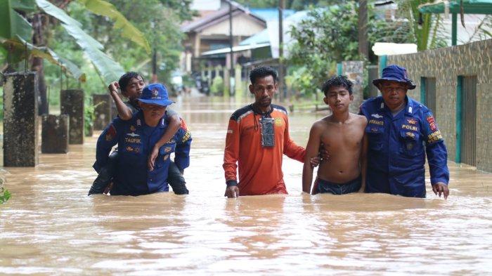 Personel Dit Polairud Polda Kaltim Bripka Taufik Ismail didampingi rekannya mengevakuasi warga yang terdampak banjir di Gang Mandor Kilometer 18, RT 13 Balikpapan Utara, Selasa (2/1/2024). 
