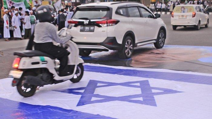 Sejumlah pengguna jalan menginjak bendera Zionis Israel dalam aksi Cinta Palestina di kawasan badan jalan simpang Mall Lembuswana Worvo, Kecamatan Samarinda Ulu, Kota Kalimantan Timur, Sabtu (13/1/2024). Saat aksi Stop Genosida Gaza Palestina oleh sekitar 500 massa dari Forum Masyarakat Cinta Palestina.