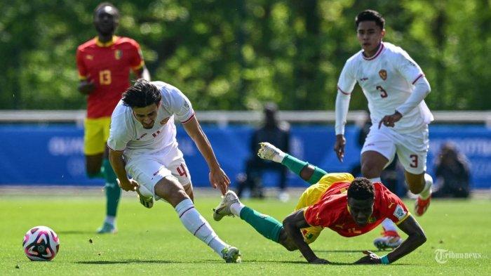Bek Indonesia (4) Nathan Tjoe-A-On (Kiri) berebut bola dengan bek Guinea (5) Saidou Sow (kanan) pada pertandingan play-off pra-Olimpiade antara Indonesia dan Guinea, untuk memperebutkan tempat terakhir di turnamen sepak bola Olimpiade putra di Paris 2024, di Clairefontaine-en-Yvelines, selatan Paris, pada 9 Mei 2024.