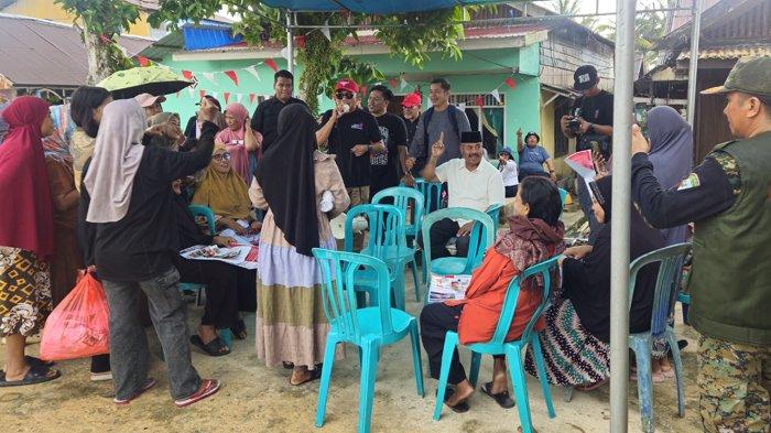 Calon Bupati Kutai Kartanegara (Kukar) Edi Damansyah duduk bersama warga di bawah tenda sederhana yang memayungi mereka dari gerimis di Desa Badak Baru, Kecamatan Muara Badak, Kukar, Senin (4/11/2024).