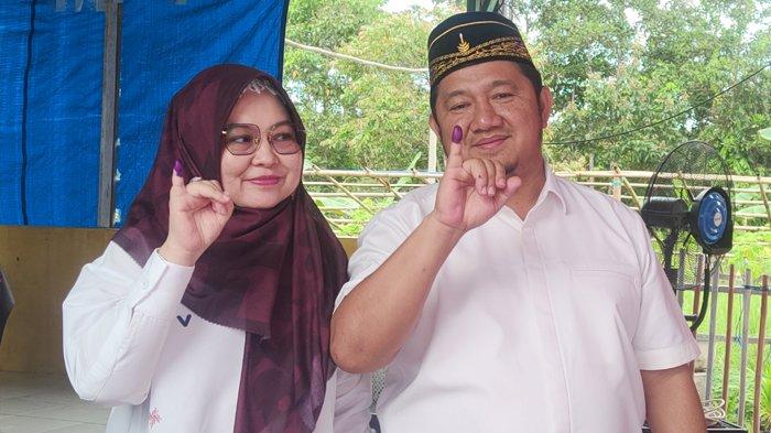 Calon Bupati Penajam Paser Utara Mudyat Noor bersama istri memamerkan jari tangan bertinta ungu usai mencoblos di TPS Sungai Parit pada gelaran Pilkada PPU 2024, Rabu (27/11/2024) pagi.