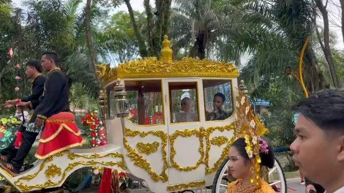 KERETA KENCANA PENGANTIN - Pengantin wanita yang merupakan anak sulung Walikota Balikpapan, Cindara Rahmad bersama pengantin pria Abdurrahman mengendarai kereta kencana menuju lokasi resepsi di Gedung BSCC Dome, Balikpapan, Kalimantan Timur, Sabtu (14/12/2024). TRIBUNKALTIM.CO/ARY NINDITA INTAN