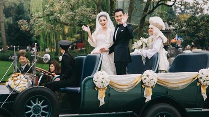 Artis peran Sandra Dewi dan suaminya, Harvey Moeis, menggunakan mobil atap terbuka saat menuju kastil Cinderella di Disneyland, Tokyo, Jepang, Senin (14/11/2016).