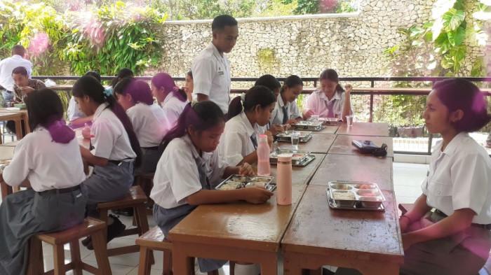 TERIMA KELUHAN-Pengawas layanan MBG menyatakan siap menerima keluhan siswa terkait layanan makanan bergisi gratis. Foto pengawas Yohanes Donbosco sedang awasi anak makan.