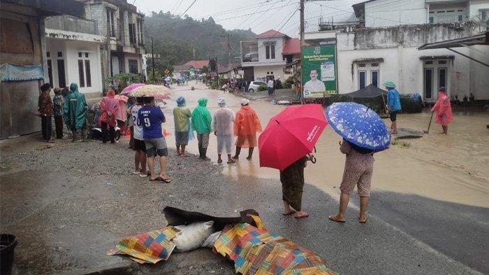 Warga menyaksikan banjir menggenang di sebuah jalan raya di Kabupaten Kerinci, Provinsi Jambi, sejak Sabtu (30/12/2023).