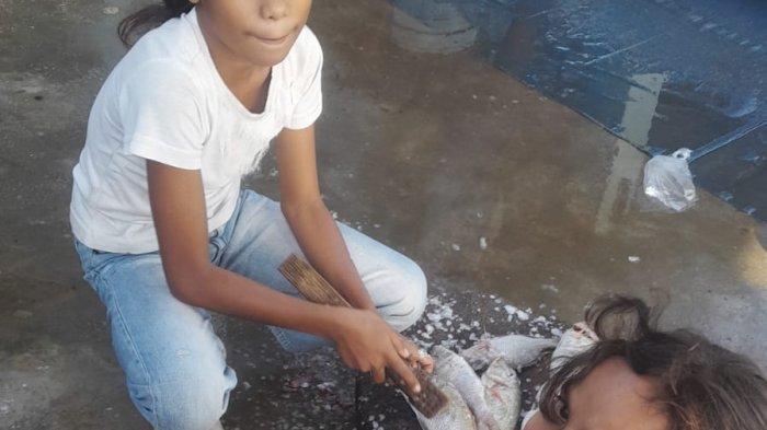 SUASANA TPI OEBA - Anak penjual tas kresek di lokasi TPI Oeba, Kelurahan Fatubesi, Kecamatan Kota Lama, Kota Kupang, Jumat 28 Juli 2023 beta minta tolong bersihkan ikan, Jumat 28 Juli 2023