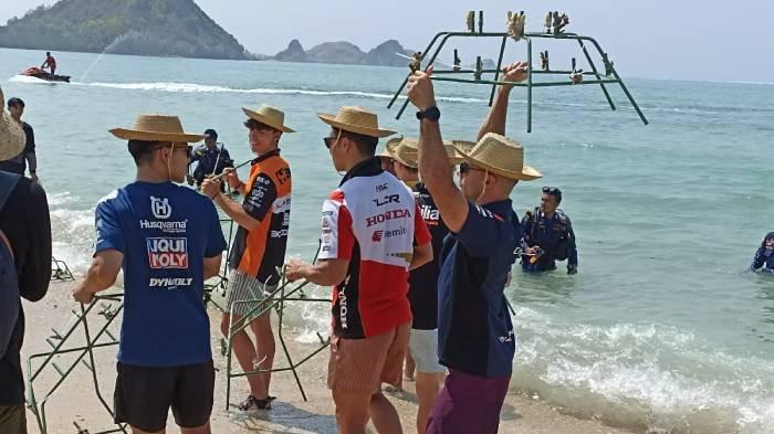 Pembalap CryptoDATA RNF MotoGP Miguel Oliveira (paling kiri) mengangkat terumbu karang yang ditanam di Pantai Kuta Mandalika, Kamis (12/10/2023).