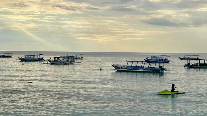 WISATA LOMBOK - Potret keindahan Pantai Nipah di Lombok Utara. Pantai Nipah menyajikan pemandangan alam yang memukau, mulai dari riak ombak yang tenang, sampan nelayan yang bersandar, hingga perbukitan hijau yang melingkupi pantai.