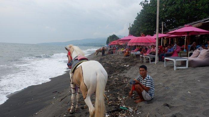 Seorang penawar jasa menunggang kuda, duduk di pasir pantai Tanjung Bias.