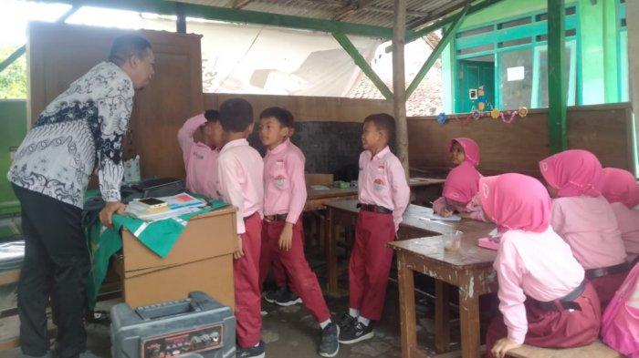 Siswa kelas 2 SDN Pengongsean 1, Kecamatan Torjun, Kabupaten Sampang, Madura saat belajar di tempat parkir karena gedung kelas nyaris roboh.