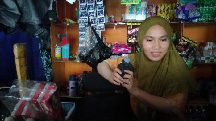 Desi (26) menunjukkan botol sambal saat menjaga toko kelontong usai viral lawan perampok bersenjata busur saat ditemui di tokonya Jl Urip Sumoharjo, Makassar, Kamis (26/11/2023) sore.