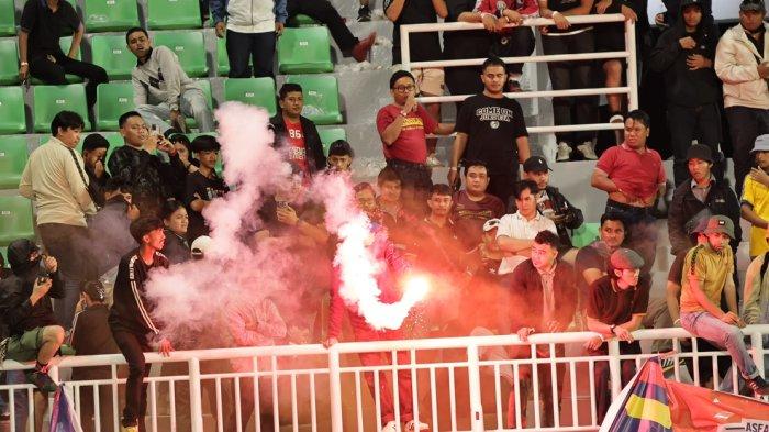 AKSI KAMPUNGAN - Seorang oknum suporter membakar flare di ujung kiri tribun terbuka Stadion BJ Habibie Parepare usai laga PSM vs CAHN FC, Rabu (2/4/2025) malam. Aksi oknum suporter tidak bertanggung jawab itu diteriaki “Kampungan… kampungan… kampungan.. “ oleh ribuan suporter lainnya.