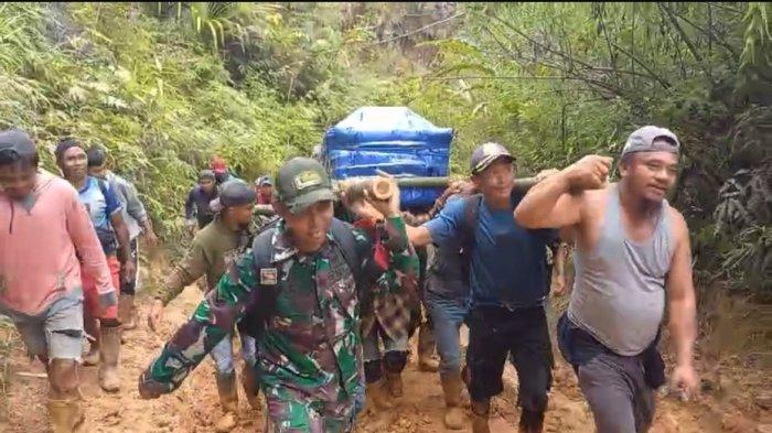 TANDU JENAZAH - Warga dan Babinsa Seko membawa peti berisi jenazah purnabakti guru menuju rumah duka di Seko, Senin (19/5/2025). Warga harus berjalan kaki sekira 30 kilometer karena kondisi jalan yang rusak.