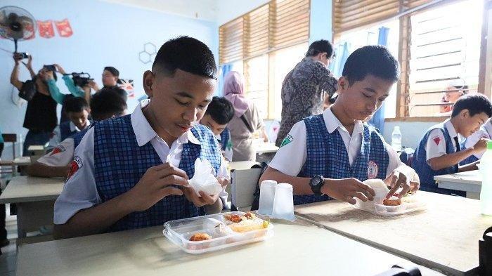MAKAN GATIS - Siswa SMP 1 Makassar mencicipi makan bergizi gratis yang di launching hari ini, Senin (6/1/2025). Makan Bergizi Gratis akan tetap dibagikan selama bulan Ramadan di Kota Makassar.