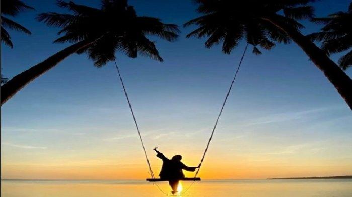 Pengunjung menikmati pemandangan sambil berayun di Pantai Sunari di Tile-tile, Kecamatan Bontoharu, Kabupaten Selayar, Sulawesi Selatan. 