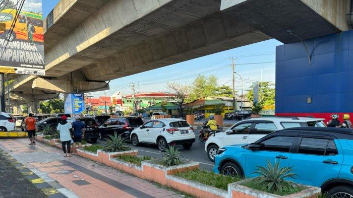 PARKIR MOBIL - Sejumlah mobil parkir di Jl AP Pettarani, untuk menuju CFD Boulevard, Minggu (18/5/2025). Jukir mematok harga parkir Rp 10 ribu untuk roda empat.