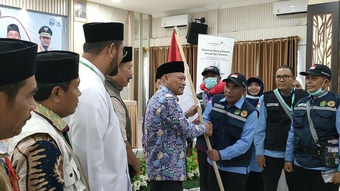HAJI 2025 - Wakil Gubernur Maluku Utara (Malut), Sarbin Sehe menyerahkan bendera merah putih simbol pelepasan Jamaah Haji, di Aula Mina Asrama Haji Emberkasi Makassar. Minggu (11/4/2025). Ia menegaskan bahwa ketua regu dan rombongan adalah jamaah yang beribadah sambil bertugas, sehingga tanggung jawab pelayanan harus dijalankan sebaik-baiknya.