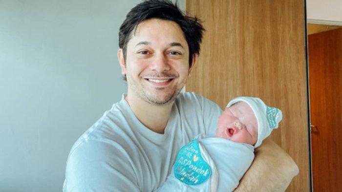 Andrew Andika saat menggendong anak keduanya yang baru lahir