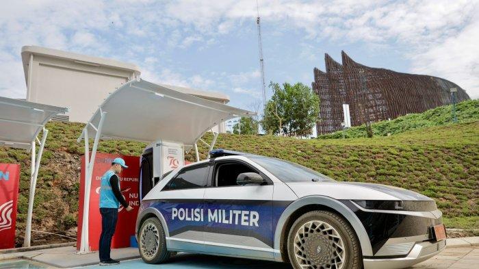 Petugas PLN sedang melakukan pengisian daya mobil listrik Polisi Militer di SPKLU Kementerian Sekretariat Negara.