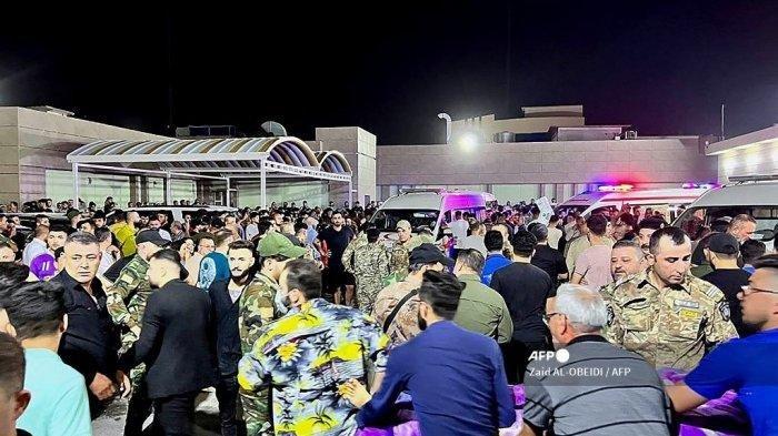 Tentara dan petugas tanggap darurat antara lain berkumpul di sekitar ambulans yang membawa orang-orang yang terluka setelah kebakaran terjadi saat pernikahan di sebuah aula acara, di luar rumah sakit umum Hamdaniyah di Al-Hamdaniyah, Irak pada 27 September 2023.