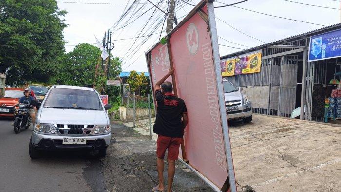 Warga membawa APK saat penertiban di jalan Tololiu Supit, Kecamatan Wanea, Manado, Senin 12 Februari 2024.