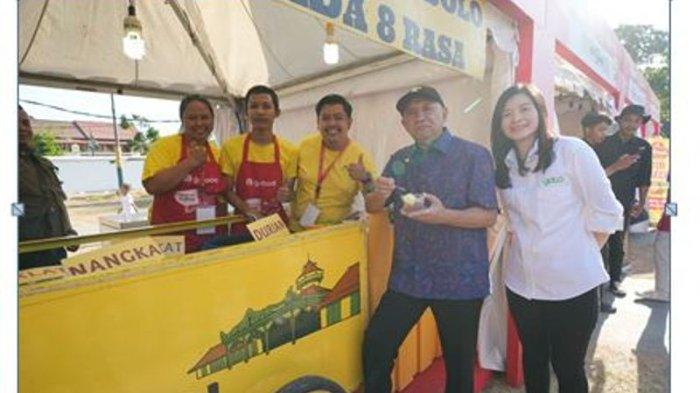 Menteri Koperasi dan UMKM Teten Masduki sedang mencicipi makanan dari salah satu mitra usaha GoFood Surya Puding didampingi oleh Direktur, Presiden E-Commerce GoTo, Melissa Siska Juminto di GoFood Petualangan Kuliner Juara Lokal Solo dalam Perayaan Hari UMKM Nasional 2023 di Solo (12/8).