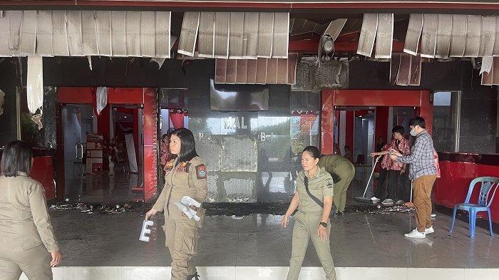 BERHAMBURAN - Satpol PP saat membersihkan material bangunan plafon bagian atas pintu utama Kantor Bupati Minut yang porak poranda pasca terbakar, Kamis (27/2/2025).