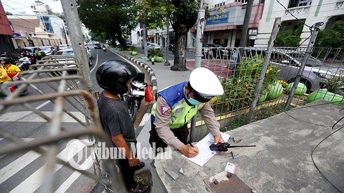 Anggota Kepolisian Korps Lalu Lintas melakukan penindakan tilang manual di simpang Jalan Pemuda, Kota Medan, Selasa (12/9). Polda Metro Jaya menyatakan kembali melakukan tilang manual untuk mengantisipasi pelanggaran lalu lintas yang tidak terekam oleh sistem tilang elektronik (ETLE).