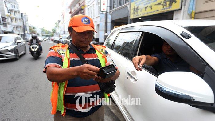 Petugas parkir elektronik (E-Parking) melayani warga yang membayar parkir melalui transaksi non tunai di Jalan Jenderal Ahmad Yani, Kesawan, Kecamatan Medan Barat, Kamis (18/4/2024). Pemko Medan dan DPRD Kota Medan menyepakati kenaikan tarif parkir, diatur dalam Perda Kota Medan Nomor 1 Tahun 2024 tentang Pajak Daerah dan Retribusi Daerah yang telah diundangkan pada tanggal 4 Januari 2024.