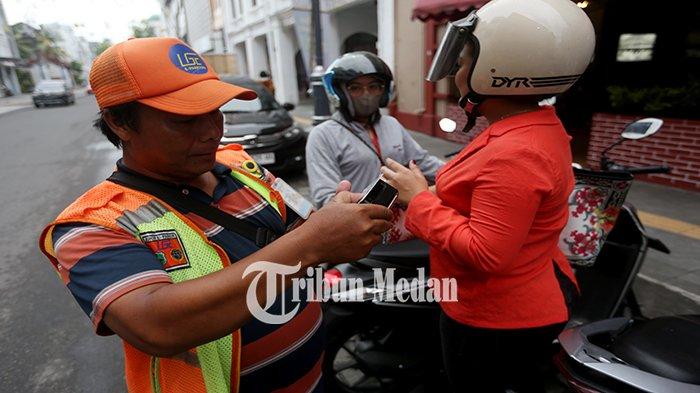Petugas parkir elektronik (E-Parking) melayani warga yang membayar parkir melalui transaksi non tunai di Jalan Jenderal Ahmad Yani, Kesawan, Kecamatan Medan Barat, Kamis (18/4/2024). Pemko Medan dan DPRD Kota Medan menyepakati kenaikan tarif parkir, diatur dalam Perda Kota Medan Nomor 1 Tahun 2024 tentang Pajak Daerah dan Retribusi Daerah yang telah diundangkan pada tanggal 4 Januari 2024.