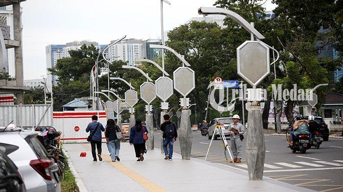 Warga berjalan kaki diatas trotoar di Jalan Pangeran Diponegoro, Kecamatan Medan Polonia, Kota Medan, Rabu (22/11). Lansekap Lampu Hias atau dikenal dengan Lampu Pocong milik Pemko Medan yang dinyatakan sebagai proyek gagal oleh Wali Kota Medan Bobby Nasution, sampai saat ini masih berdiri tegak di beberapa ruas jalan di Kota Medan.
