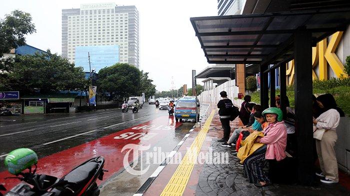 Sejumlah warga menunggu bus Trans Metro Deli di halte Jalan Guru Patimpus, Kota Medan, Rabu (27/9). Balai Besar Meteorologi, Klimatologi, dan Geofisika (BMKG) Wilayah I Medan mengeluarkan peringatan dini waspada potensi hujan lebat yang dapat disertai petir dan angin kencang di wilayah Sumatera Utara.