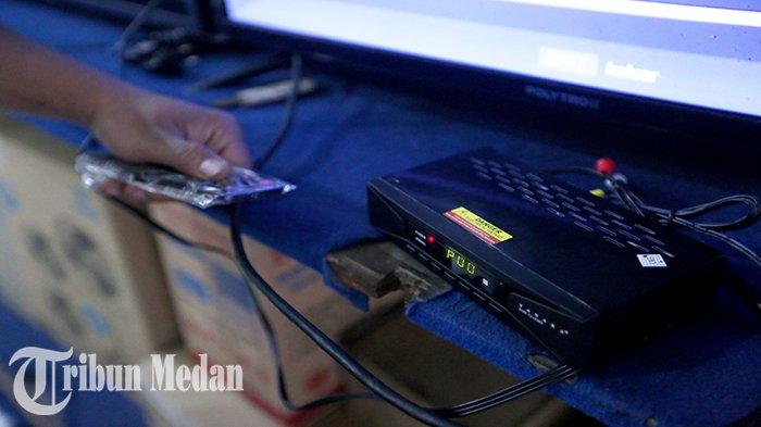 Seorang pramuniaga mencoba Set Top Box (STB) baru di Abadi Electronic Jalan Brigjend Katamso, Kota Medan, Senin (31/7). Kepala Dinas Komunikasi dan Informasi (Kominfo) Kota Medan, Arrahman Pane menanggapi persoalan siaran TV analog yang mulai dimatikan per hari ini.