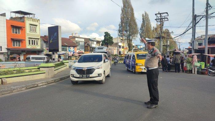 ALIHKAN JALUR ALTERNATIF : Panit I Unit Lantas Polsek Berastagi Ipda Juahta Perangin-Angin, melakukan pengaturan lalulintas di kawasan Tugu Perjuangan, Berastagi, Minggu (6/7/2025). Tingginya volume kendaraan ke jalur Medan pada libur akhir pekan ini, membuat personel sempat mengalihkan pengendara ke jalur alternatif selama satu jam.