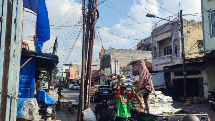 BERAS OPLOSAN- Seorang pekerja sedang mengangkat beras di Pasar Pringgan Medan, Senin (7/7/2025). Pemprov Sumut respon 13 merek beras  yang ditemukan Bareskrim Polri diduga oplosan.