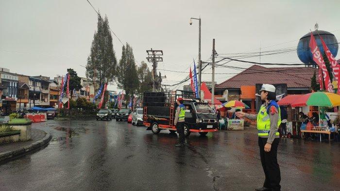 BERASTAGI DIGUYUR HUJAN : Kanit Lantas Polsek Berastagi Iptu Rotua Sipayung (kanan), melakukan pengaturan lalulintas di kawasan Tugu Perjuangan, Berastagi, Minggu (23/3/2025). Di akhir pekan ini Berastagi diguyur hujan sejak pagi, Polres Tanah Karo mengimbau pengendara agar selalu waspada.