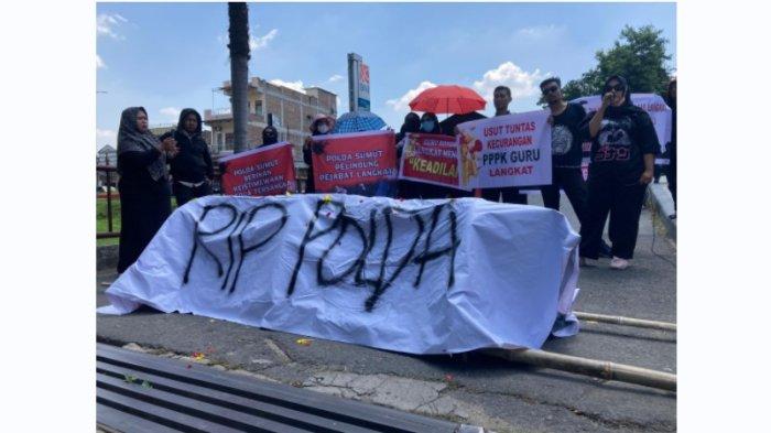 Belasan guru honorer dari Kabupaten Langkat, Sumatera Utara saat berunjukrasa di depan pintu masuk Polda Sumut, Rabu (5/6/2024) siang. Mengenakan pakaian serba hitam dan bawa keranda mereka mendesak Polda Sumut mengusut tuntas dugaan kecurangan rekrutmen PPPK yang terjadi.