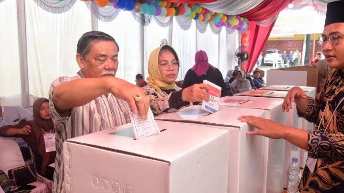 Bupati Deli Serdang, M Ali Yusuf Siregar dan istri memasukkan kertas suara ke kotak usai mencoblos dekat rumahnya Rabu, (14/2/2024).