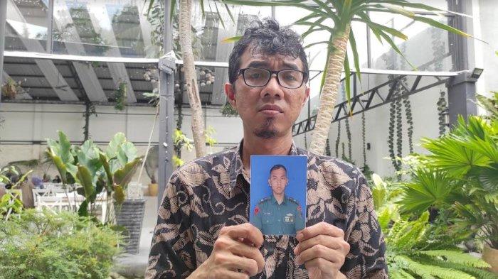 Dedi, saat memegang foto mendiang adiknya Lettu Laut Kesehatan TNI Angkatan Laut (AL) bernama dr Eko Damara (31) yang ditemukan tewas di Poskotis Satgas Mobile, RI-PNG Yonif 7 Marinir, Kabupaten Yahukimo, Papua Pegunungan pada 27 April 2024 lalu. Keluarga menduga Eko dibunuh, bukan bunuh diri.