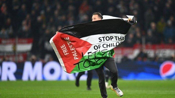 AKSI SUPORTER- Seorang penggemar berlari ke lapangan dengan membawa bendera Palestina bertuliskan: 